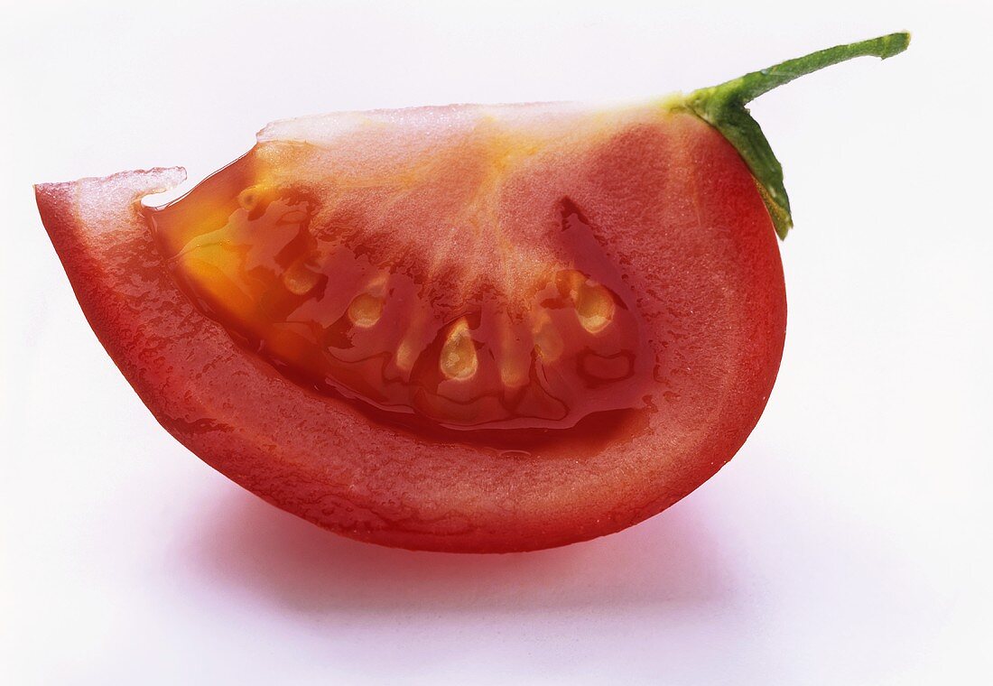 Ein Tomatenschnitz mit Stiel auf weißem Untergrund