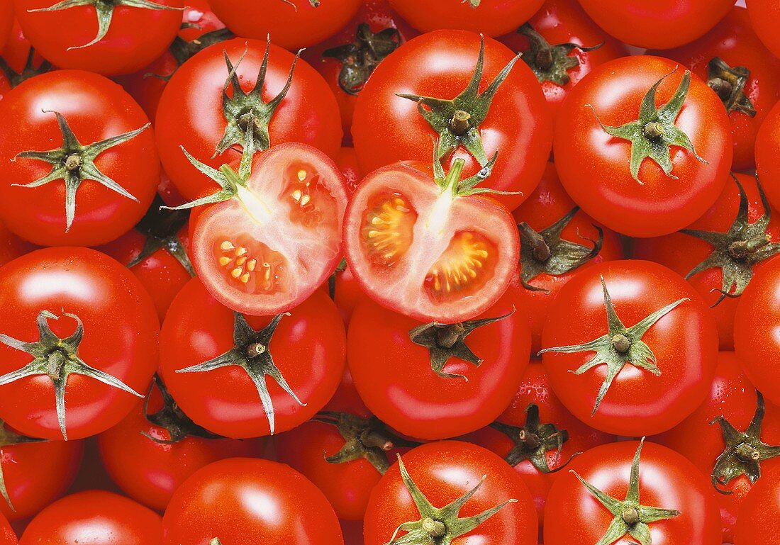Viele Tomaten, in Reihen gelegt, mit zwei Tomatenhälften