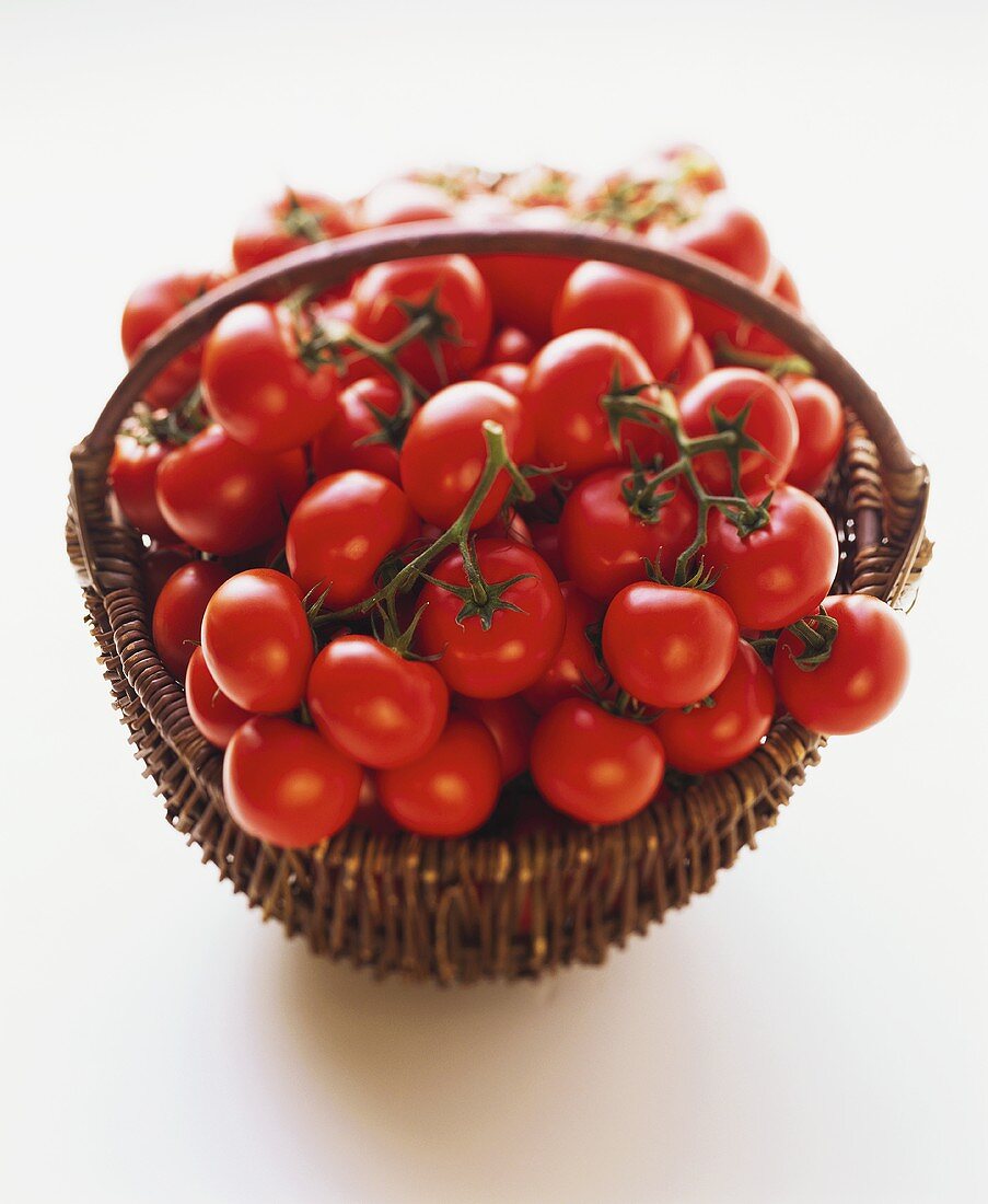 Lots of vine tomatoes in brown basket on white background