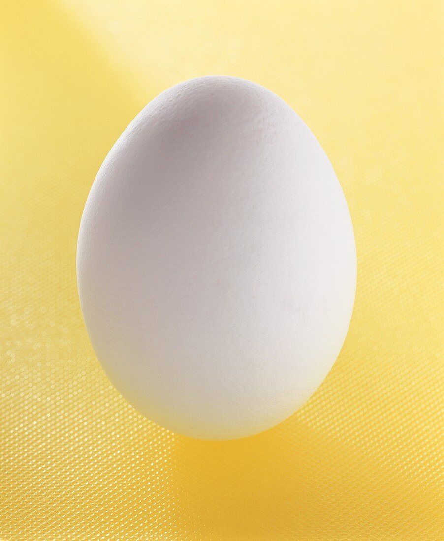 Ein weisses Ei auf gelbem Untergrund