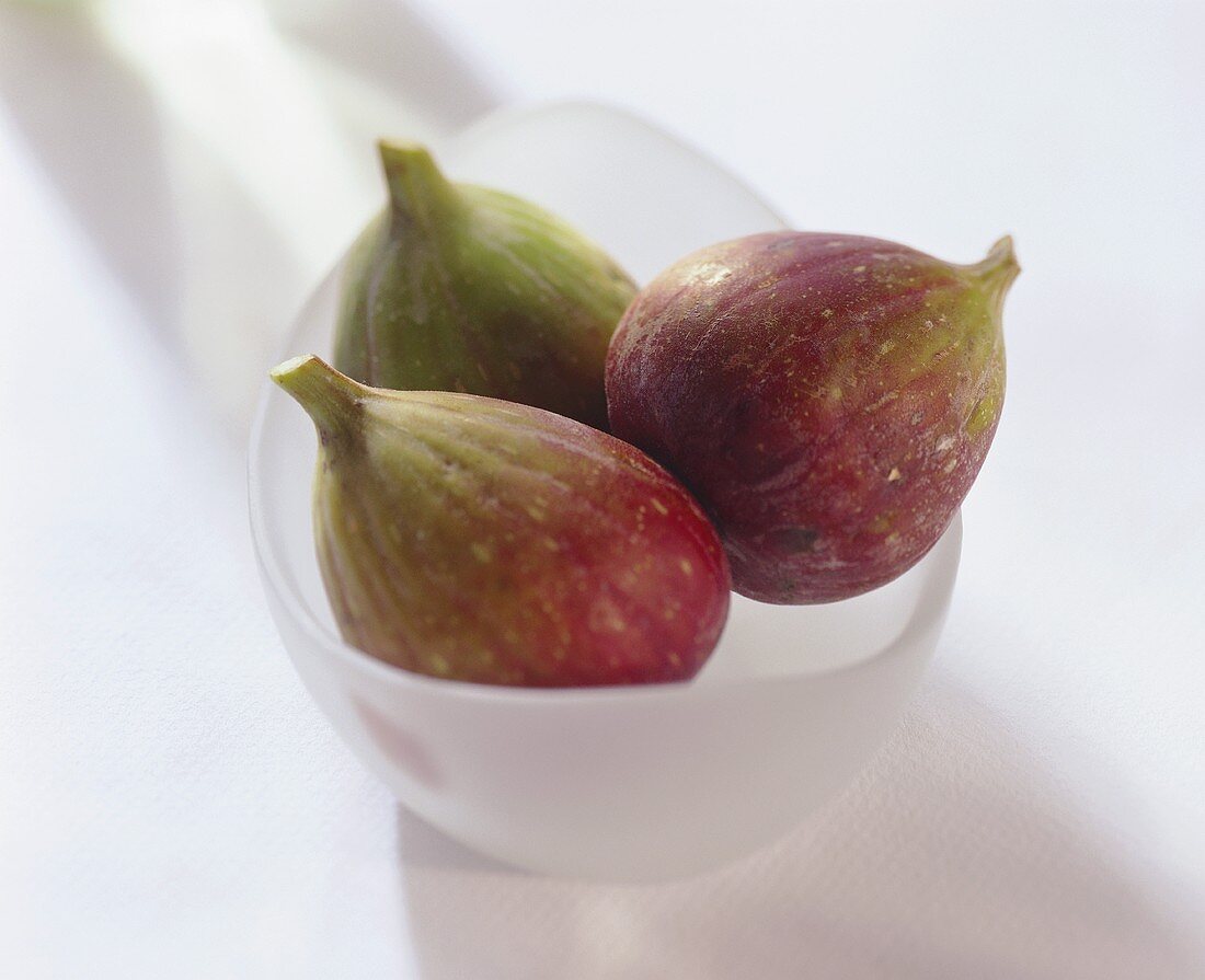 Drei frische Feigen in einem weissen Schälchen