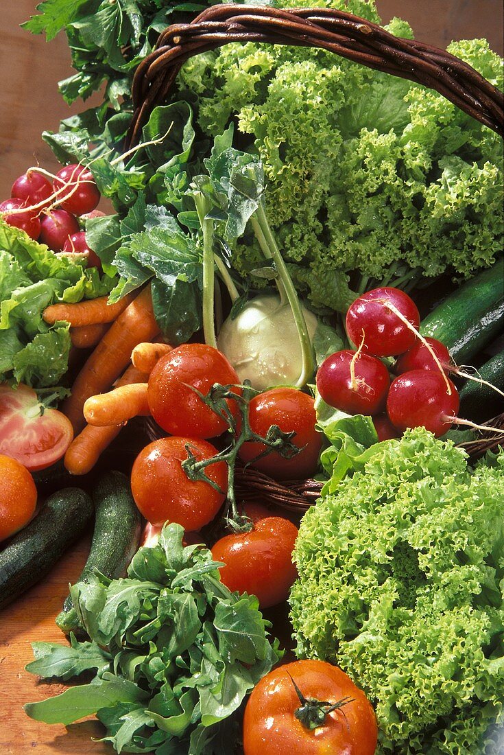 Frische Gemüsesorten und Salate in und vor einem Korb