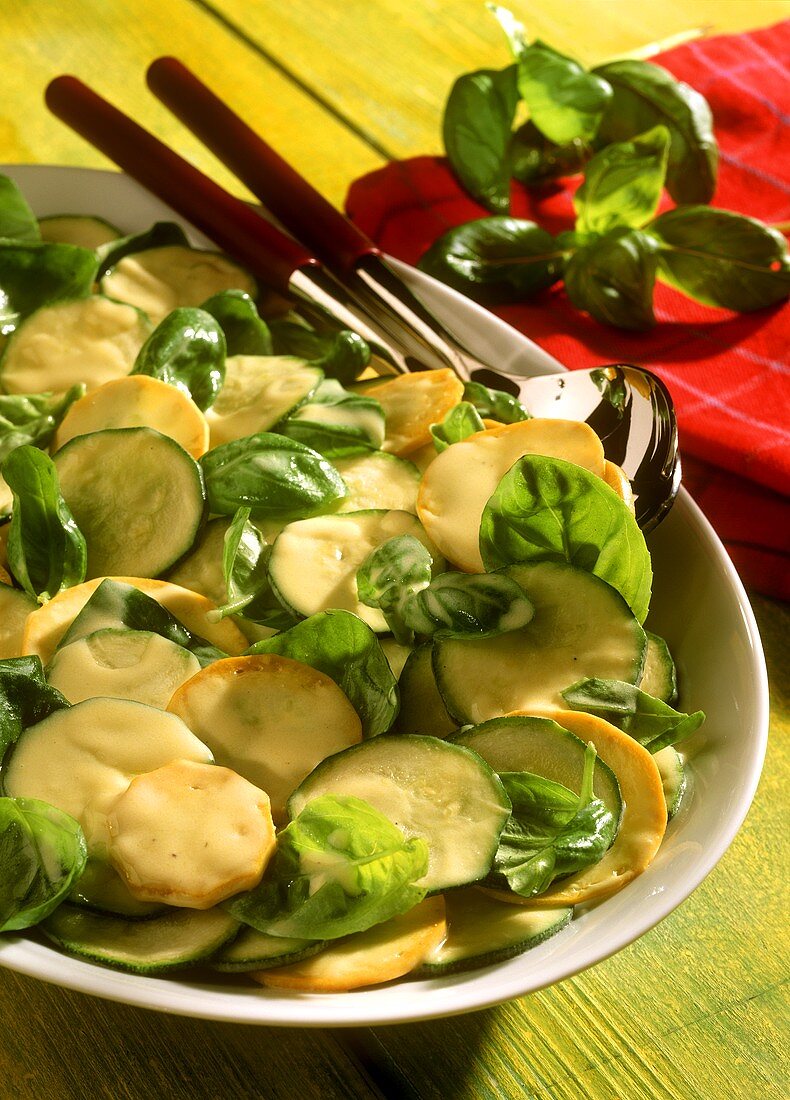 Gelbgrüner Zucchinisalat mit Basilikum auf weisser Platte