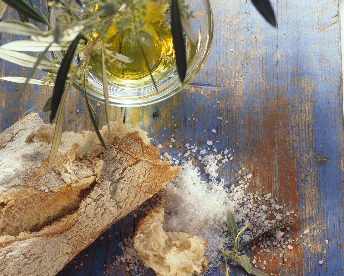Stillleben mit Olivenbaguette, Olivenöl und grobem Salz