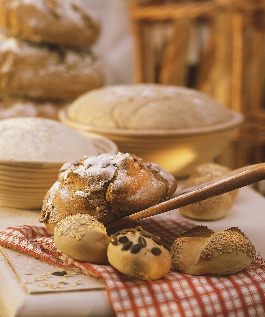 Stillleben mit Bauernbrot und Brötchen auf rotkariertem Tuch