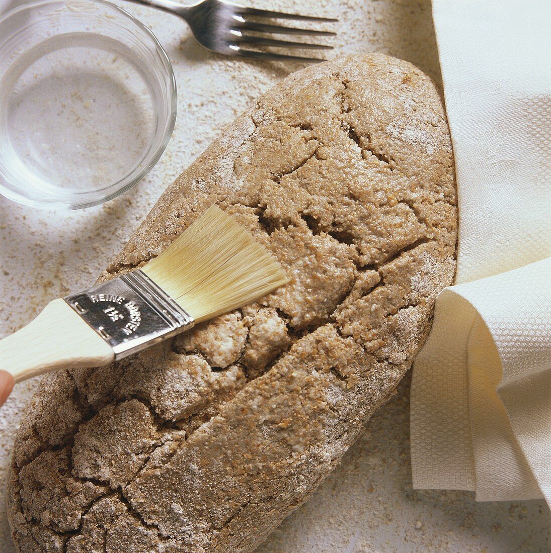Making brown bread: brushing loaf with water
