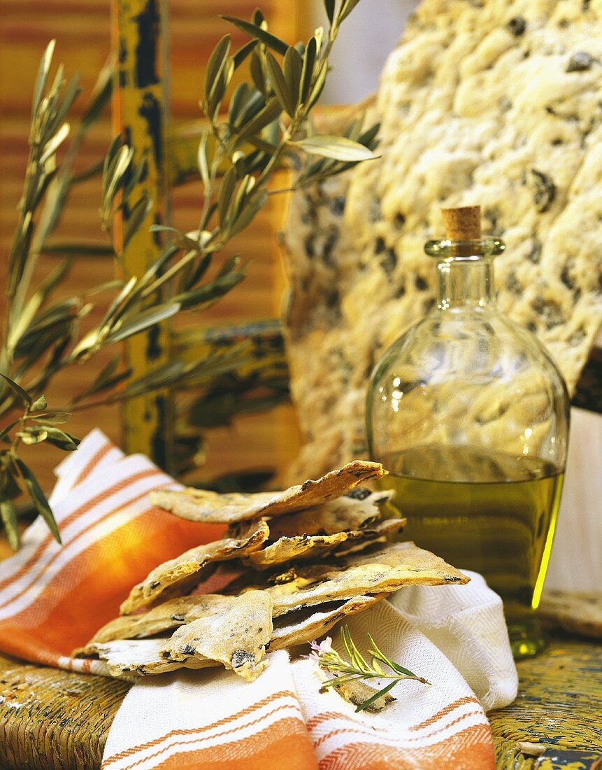 Toskanisches Olivenbrot auf Küchentuch; Olivenöl, Olivenzweig