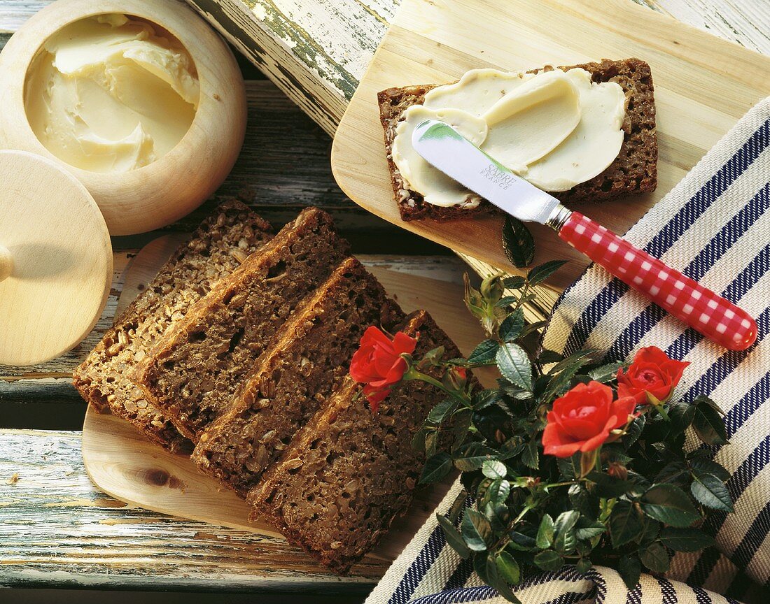 Rhenish black bread on wooden board; bread & butter; roses