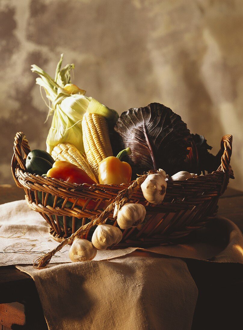Still: vegetables in basket & garlic on wooden table