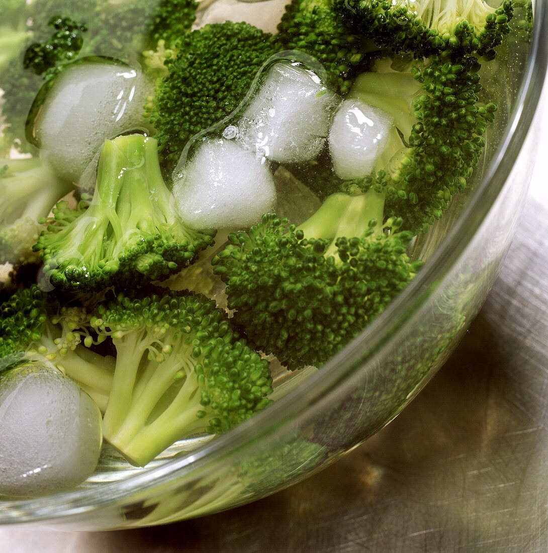 Blanched broccoli florets in dish with iced water