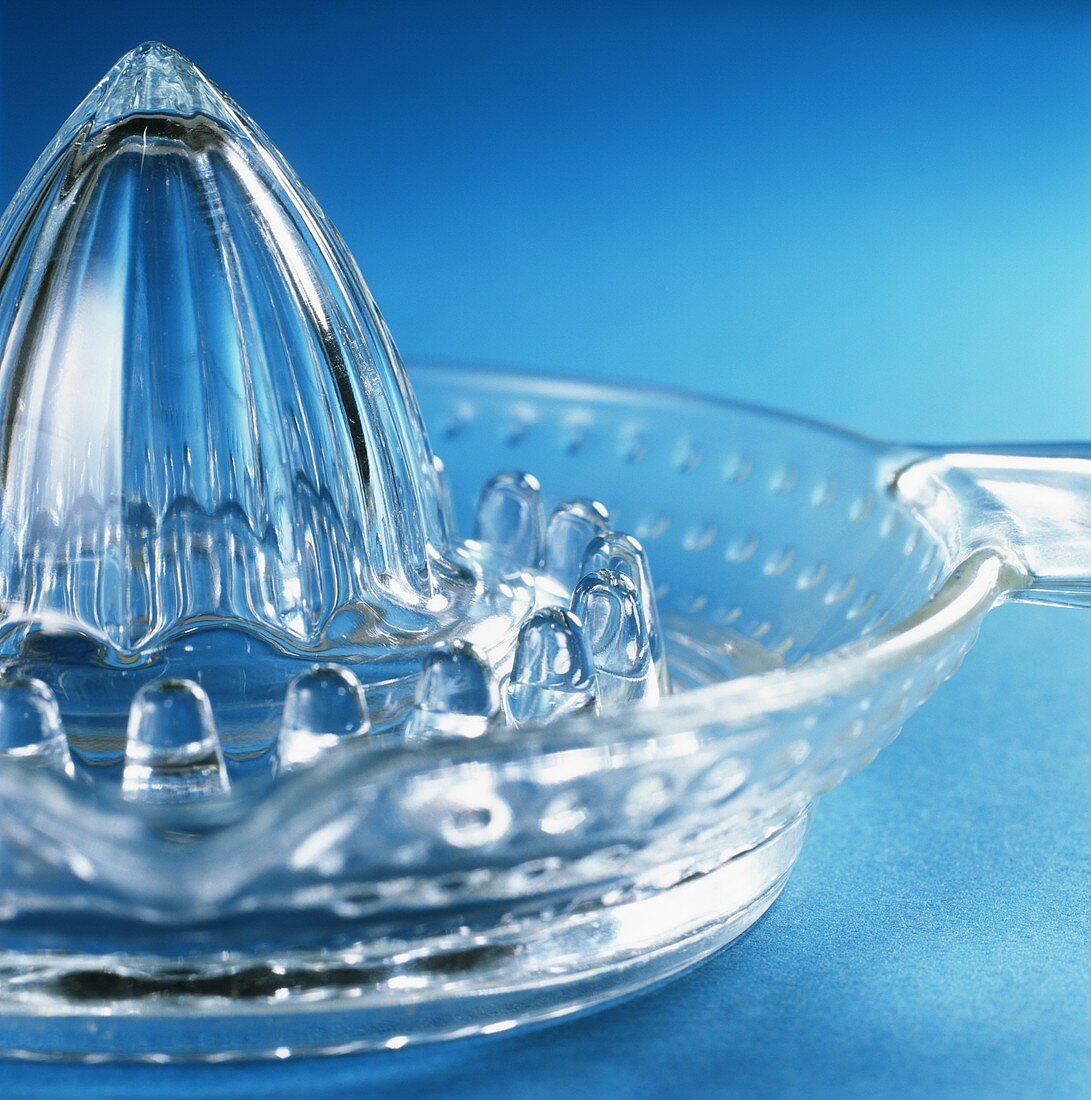 Glass lemon squeezer on a blue background