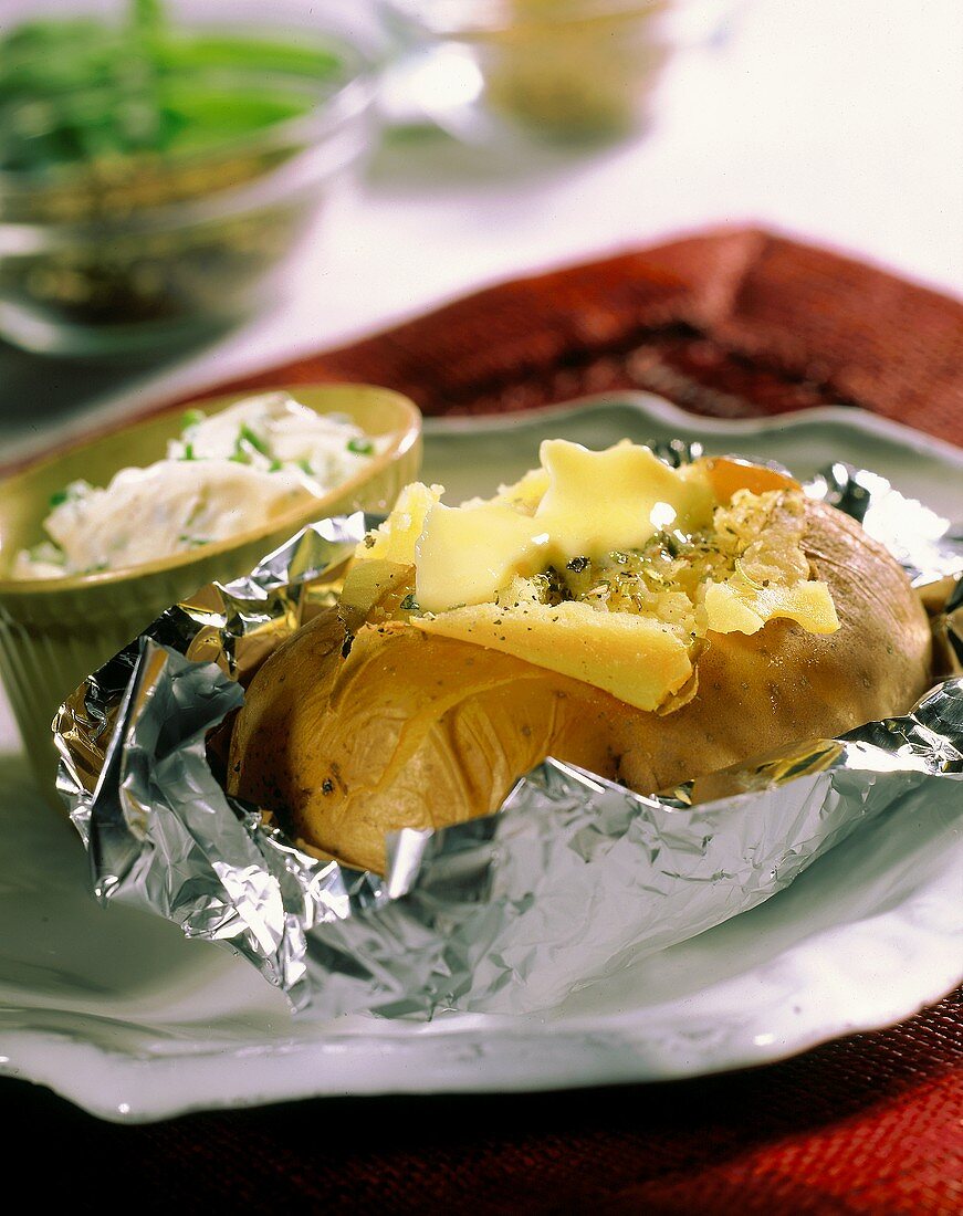 Baked potatoes in foil on plate with herb quark