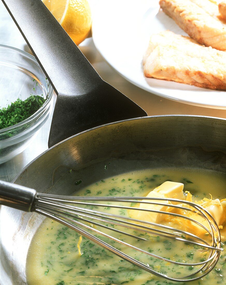 Zitronen-Kapern-Butter in Pfanne mit Schneebesen; Fischfilets