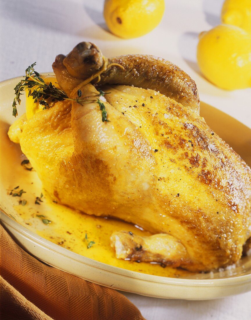 Roast chicken with lemon stuffing and thyme on a platter