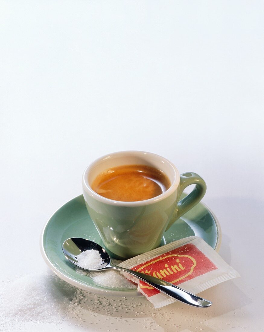 Espresso in green cup; spoon; sugar and sugar packet