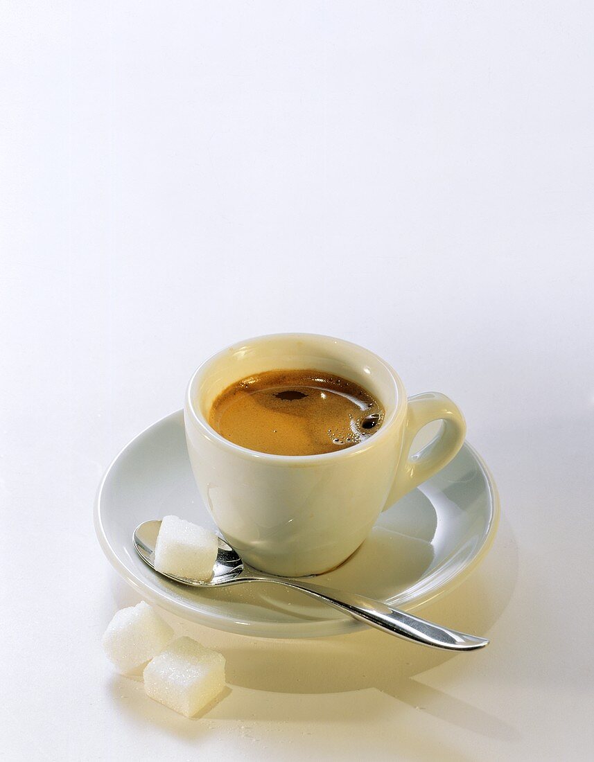 Espresso in weisser Tasse; Zuckerwürfel auf Löffel