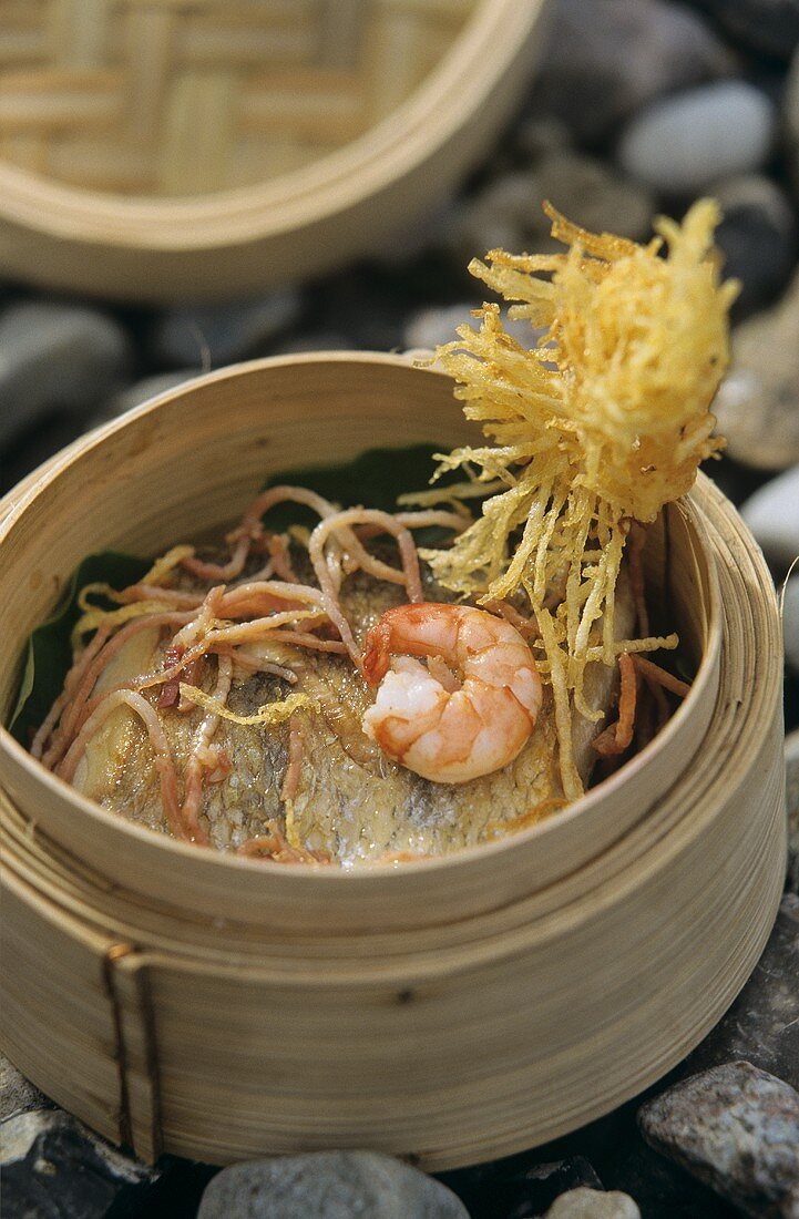 Scampi on pike-perch in bamboo steamer on stone background