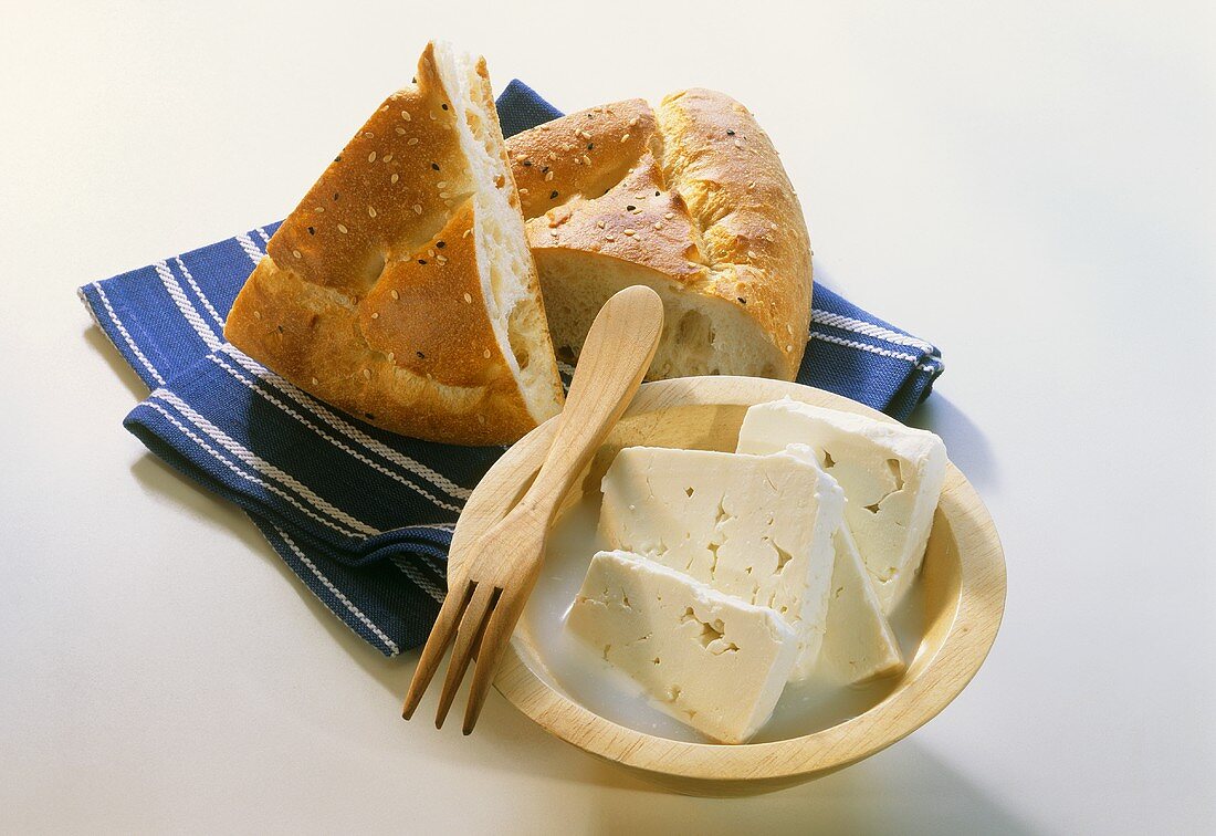 A few slices of sheep's cheese in a bowl; Flat bread