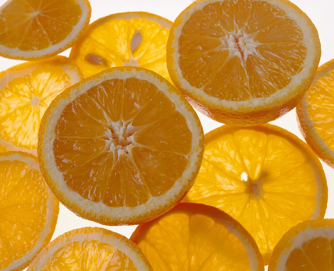 Zwei Orangenhälften und einige Orangenscheiben auf Glasplatte