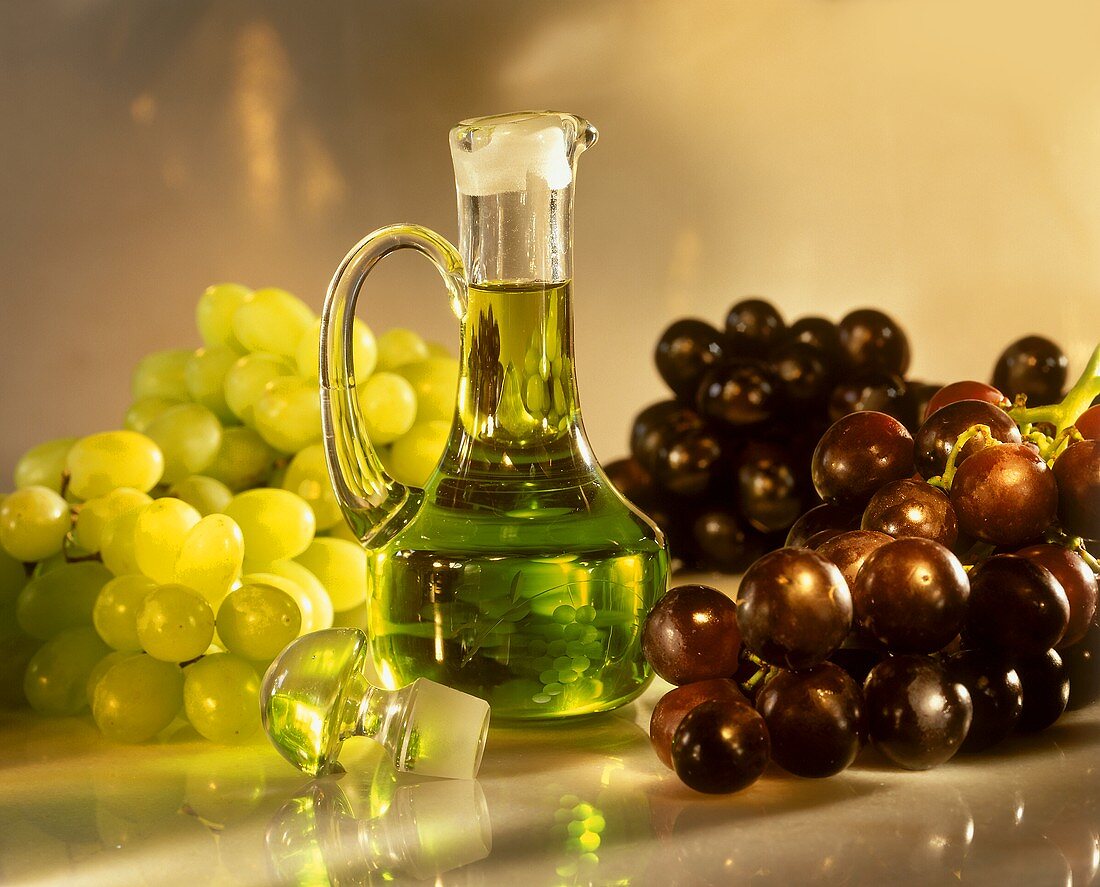 Traubenkernöl im Fläschchen, umgeben von frischen Trauben