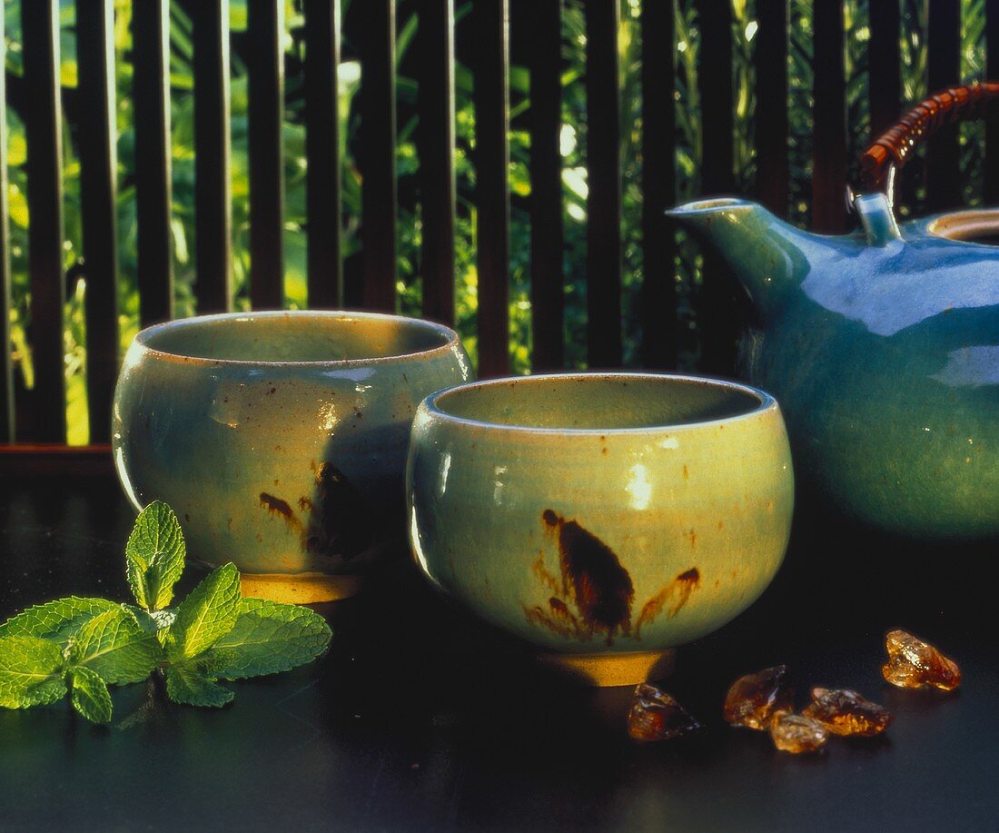 Two tea bowls and teapot; lemon balm leaves