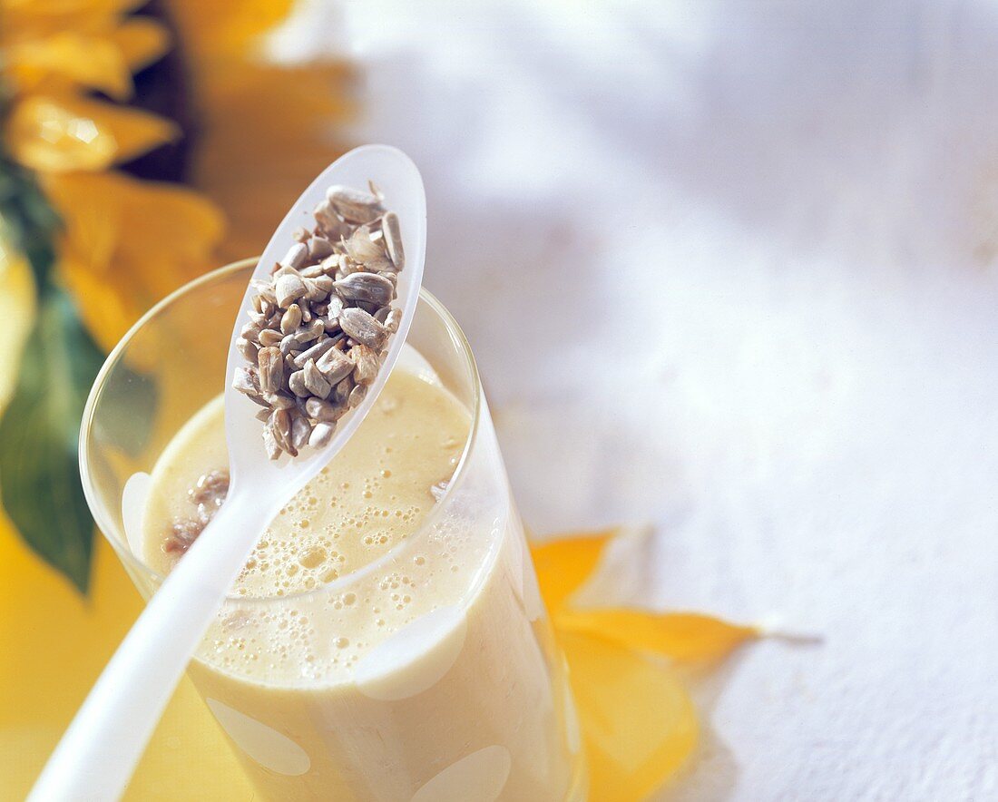 Mango ayran with sunflower seeds in glass and on spoon