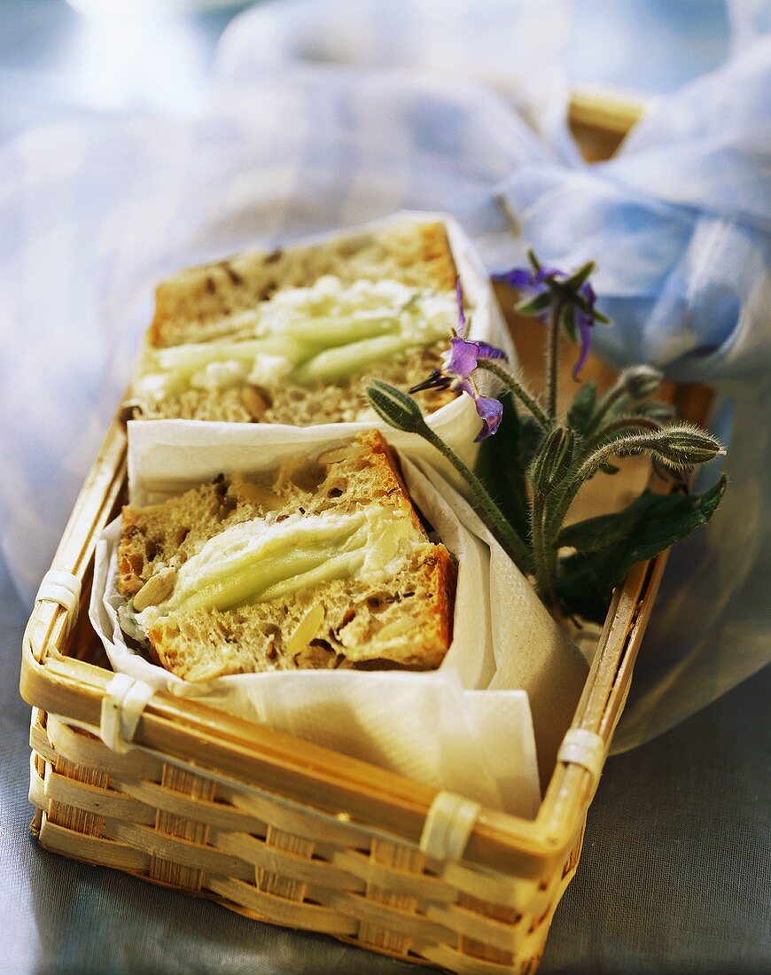 Ziegenkäse-Sandwich mit Gurke und Borretschblüte im Korb