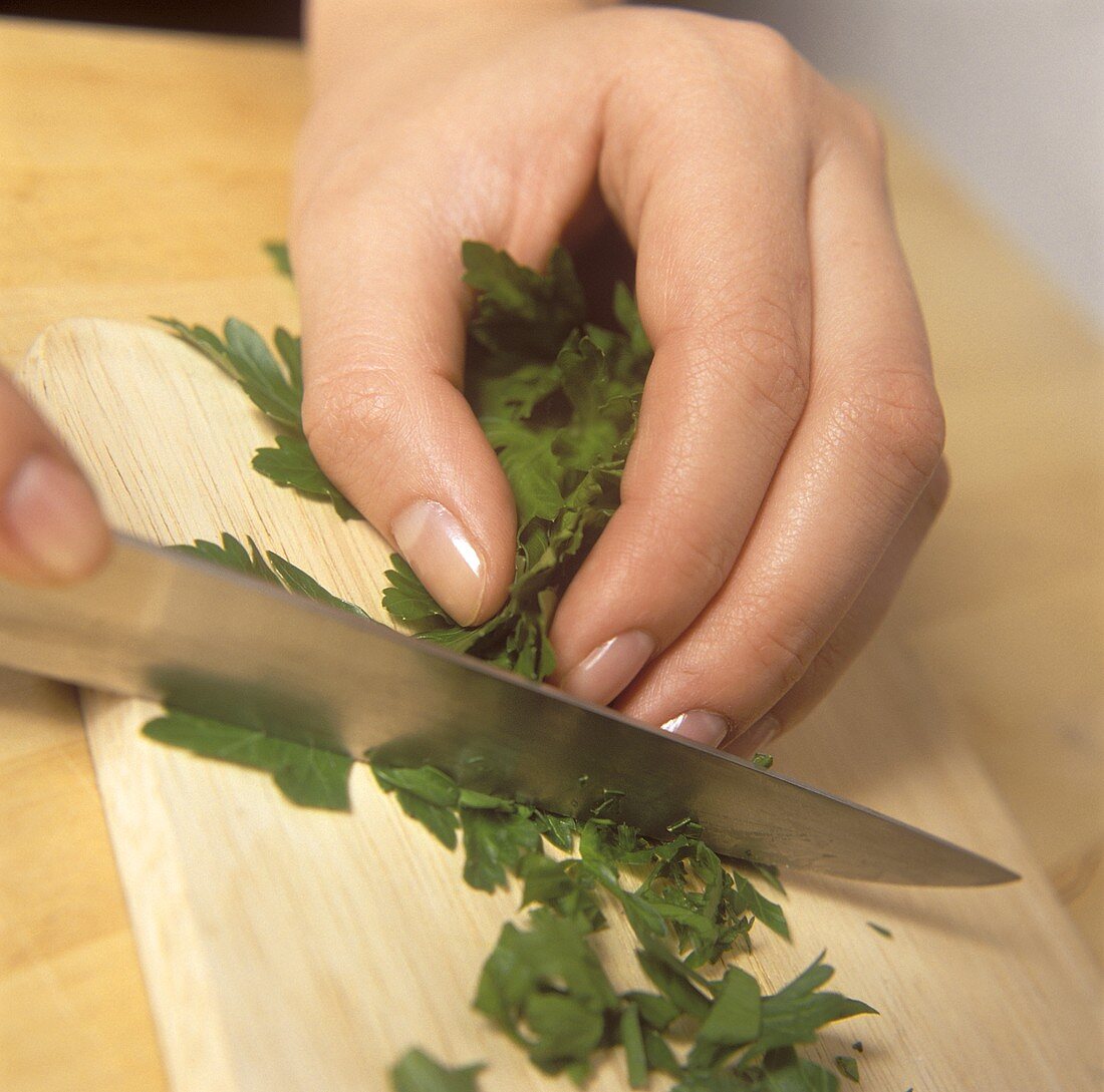 Cutting parsley on a wooden chopping board