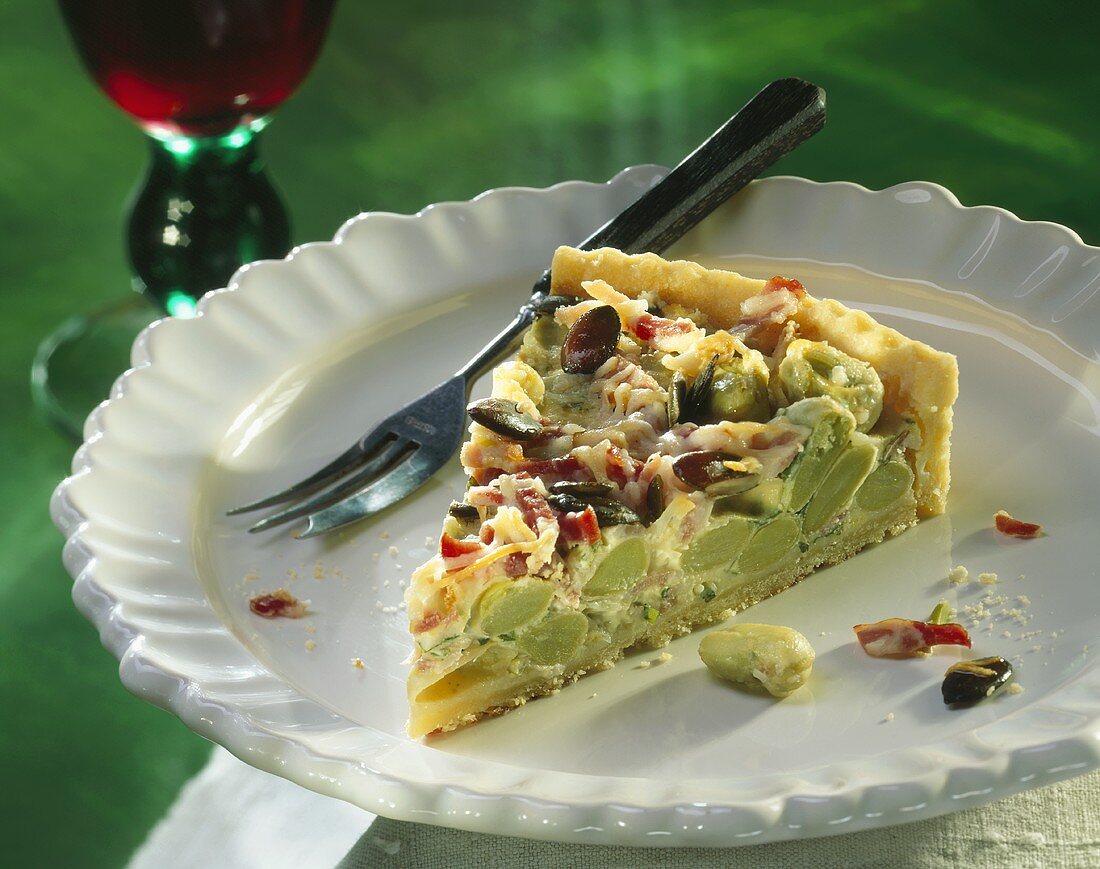 A piece of bean tart with bacon, cheese & pumpkin seeds