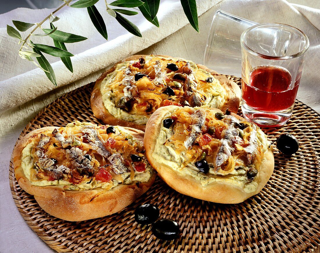 Onion flatbread with anchovies, olives & tomatoes; wine glass
