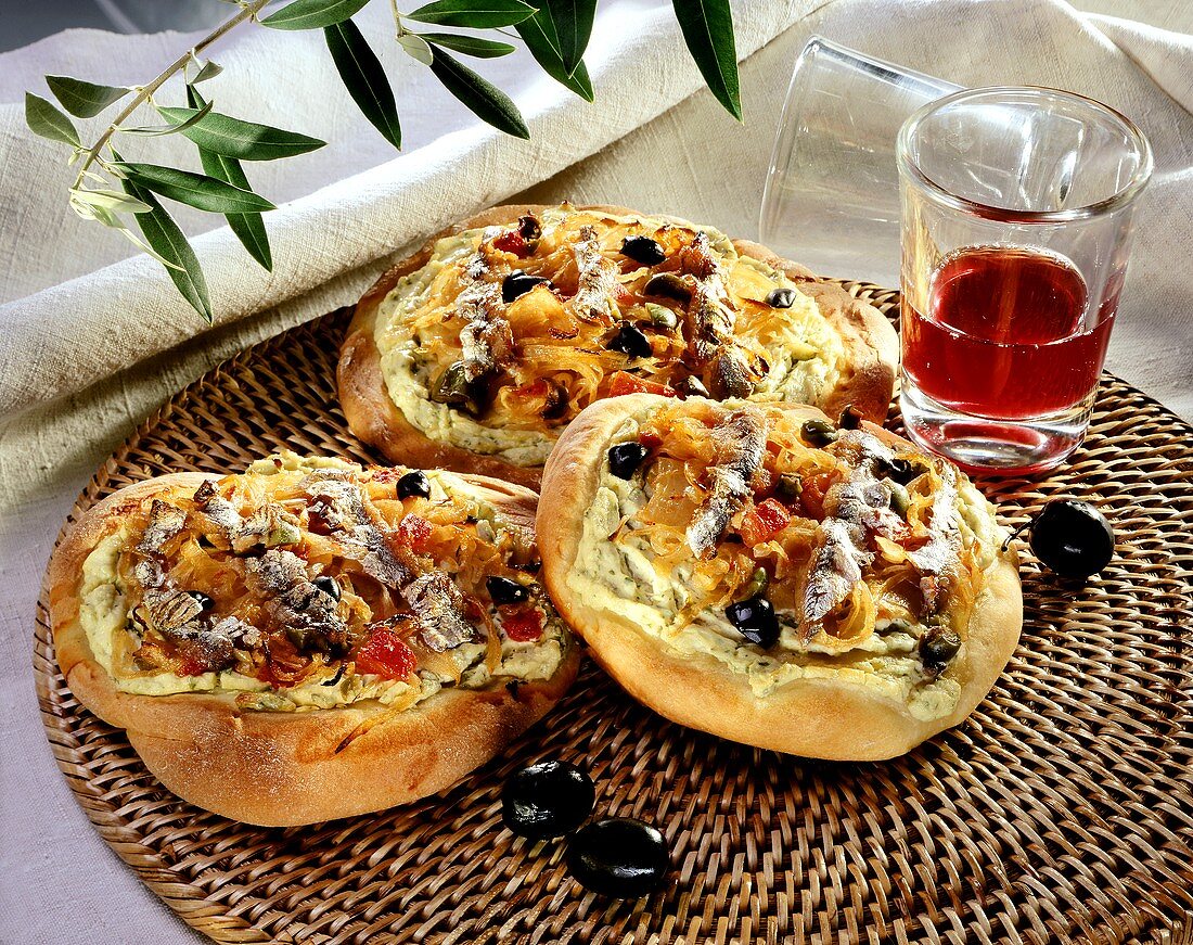 Zwiebelfladen mit Sardellen, Oliven und Tomaten; Rotweinglas