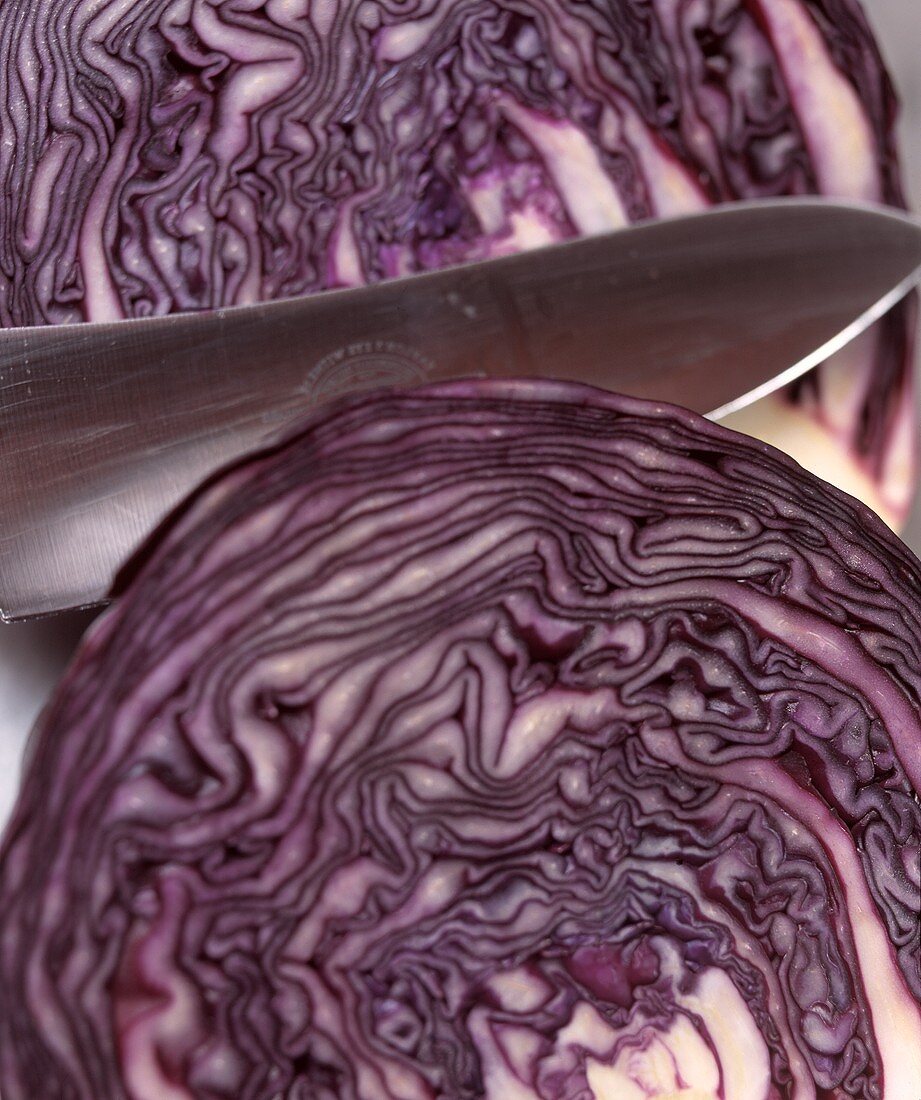 Red cabbage, cut into two halves, with knife (close-up)