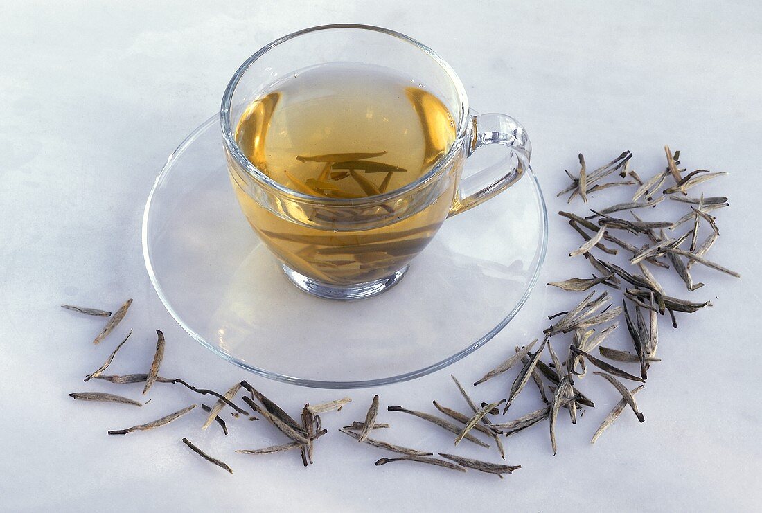 Eine Tasse grüner Tee (Ying Zeng, China) und Teeblätter