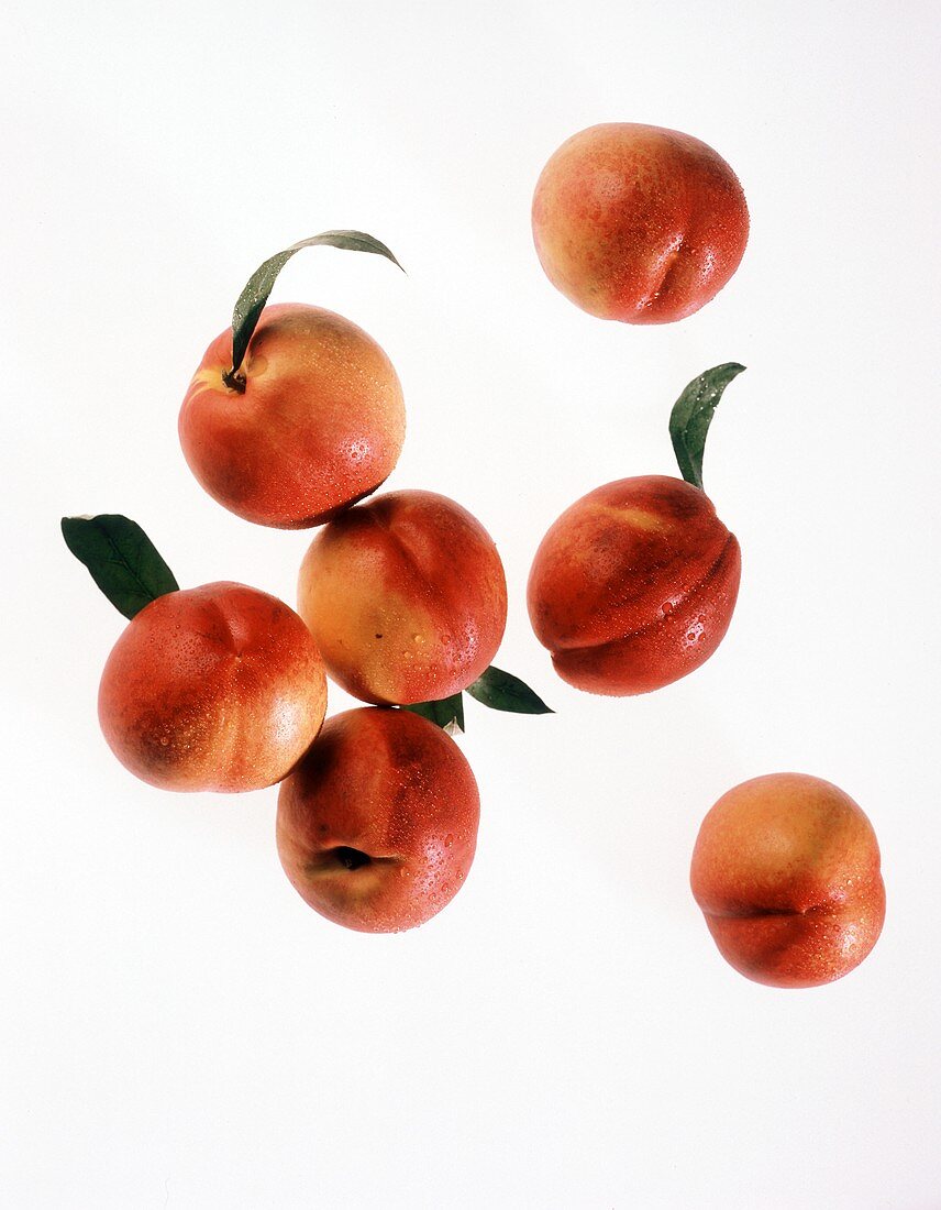 A few nectarines with drops of water and leaves