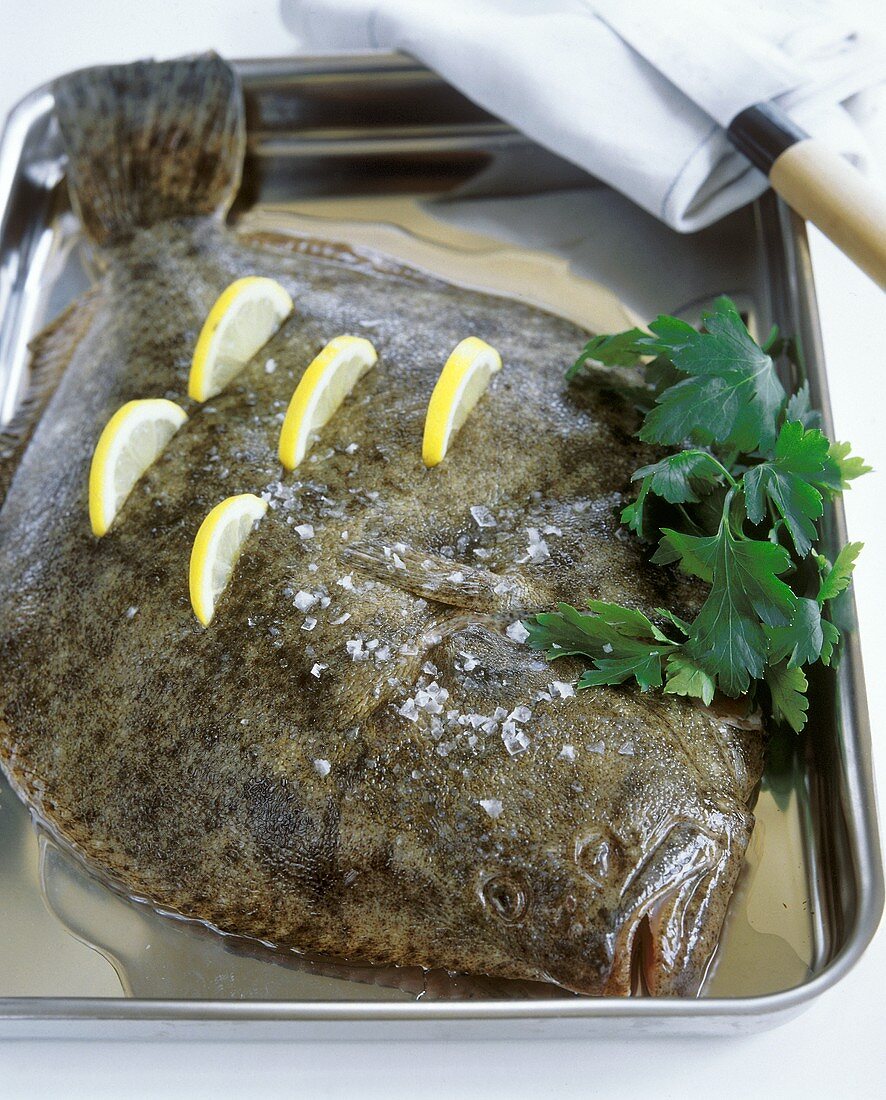 Raw turbot with salt, lemons and parsley in a roasting dish