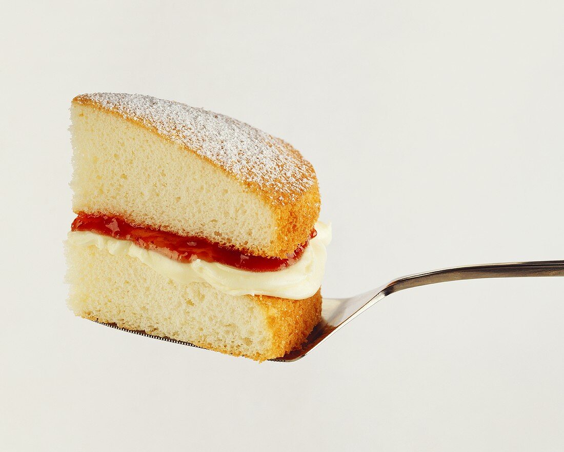 A piece of cake with a layer of cream and jam on cake slice