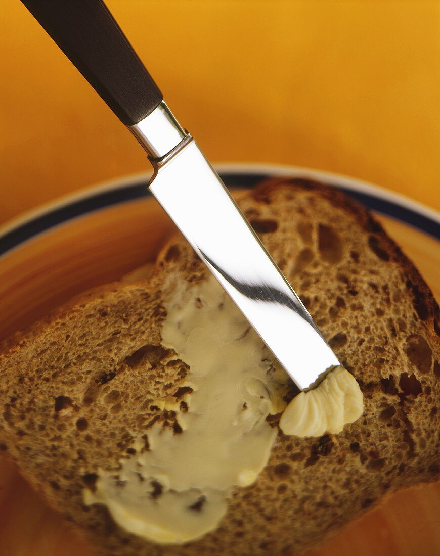Butter on knife and slice of bread