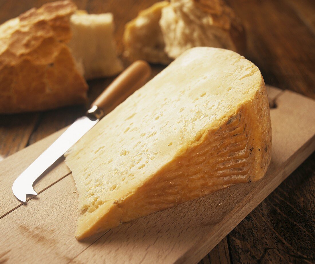 Pecorino on a chopping board with a cheese knife and bread