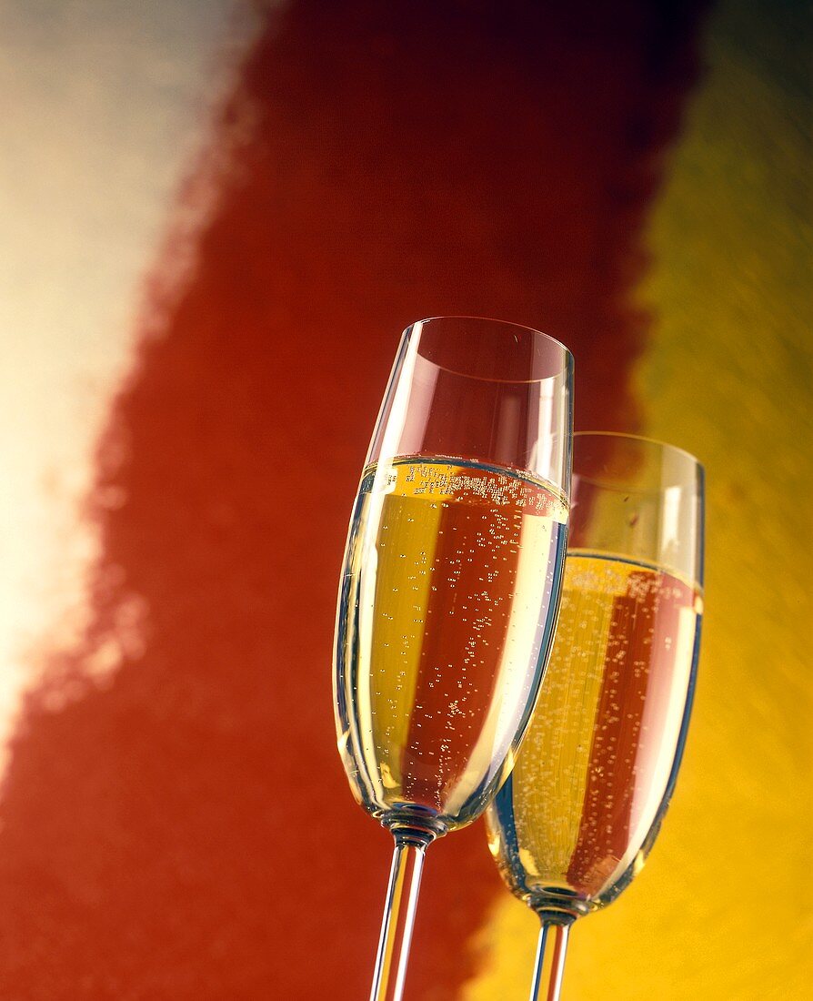 Two champagne against a red and orange painted backdrop