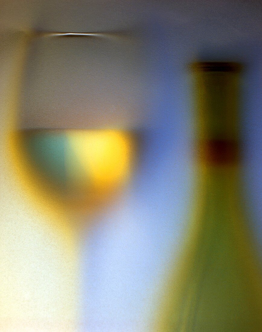 Weißwein in Glas und Flasche vor blauem Hintergrund