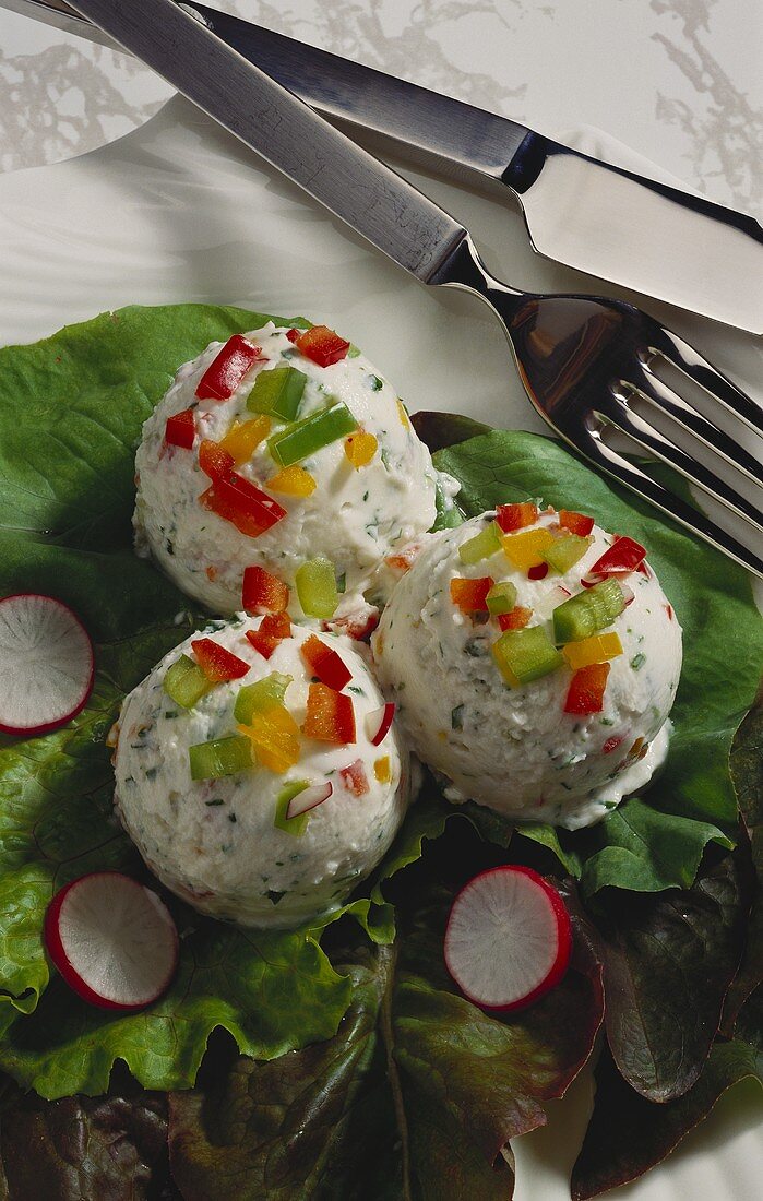 Three balls of vegetable & herb quark on salad leaves; cutlery