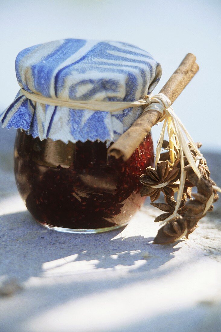 Himbeerkonfitüre im Einmachglas mit Zimtstange und Sternanis