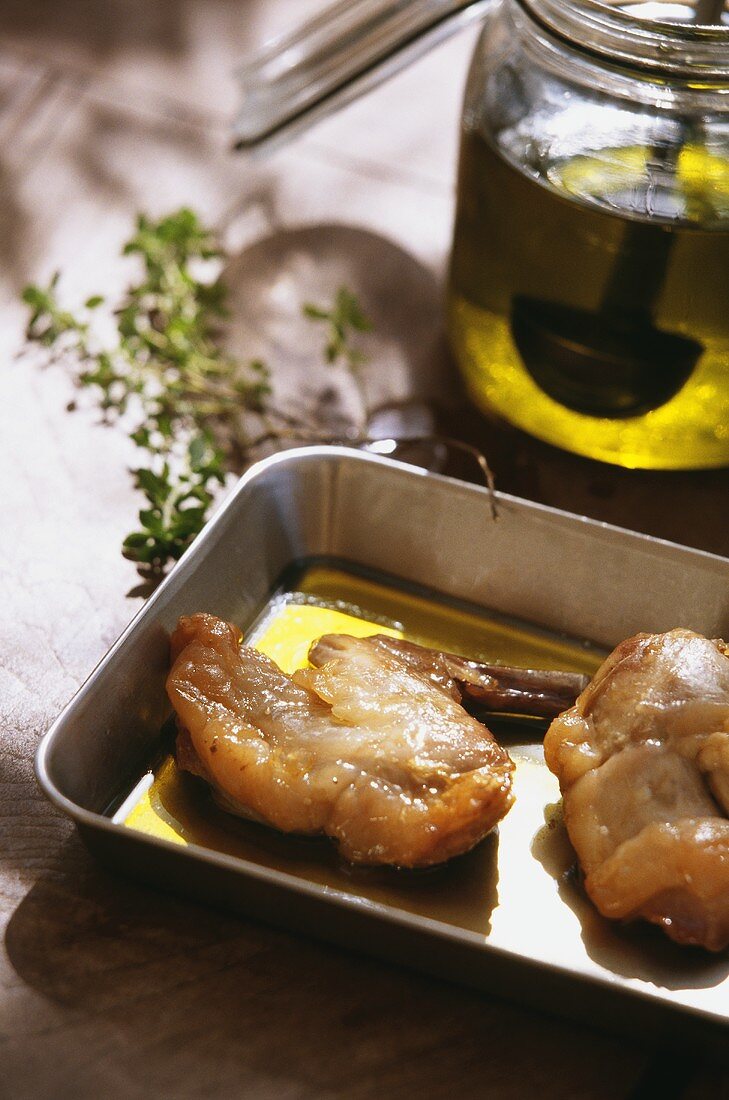 Gebratene Kaninchenteile mit wenig Olivenöl im Bräter