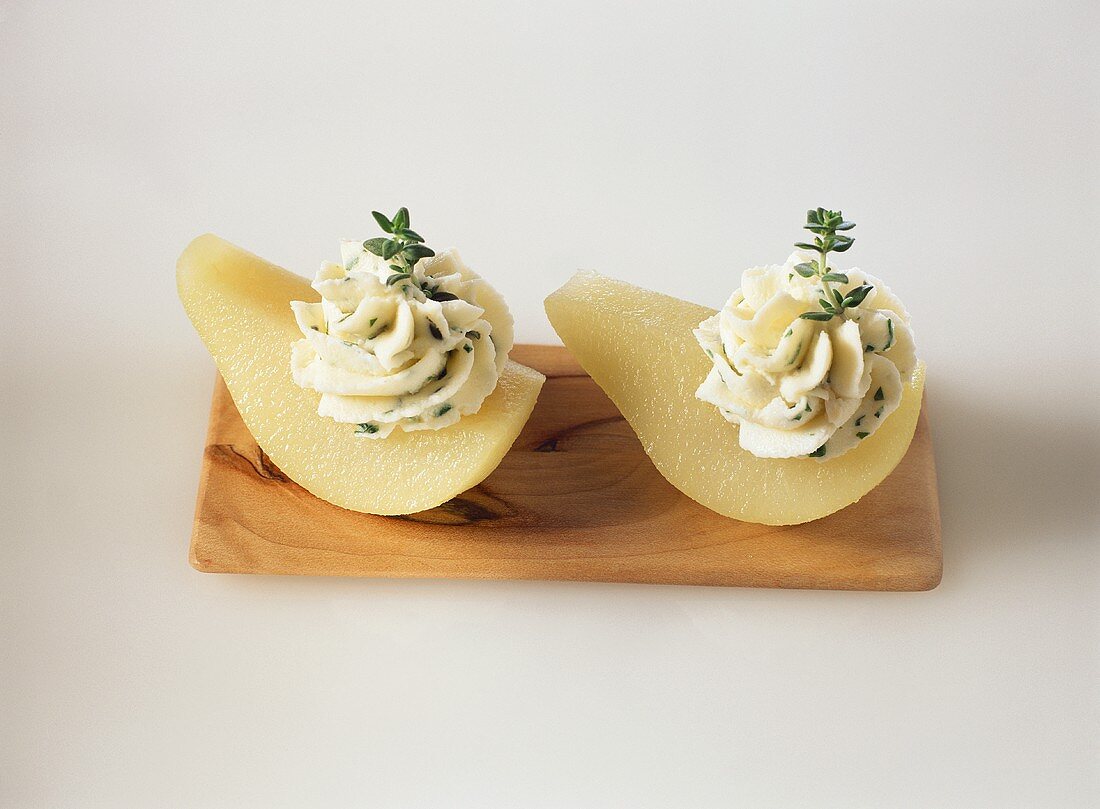 Two pears with thyme and vineyard cheese on wooden board