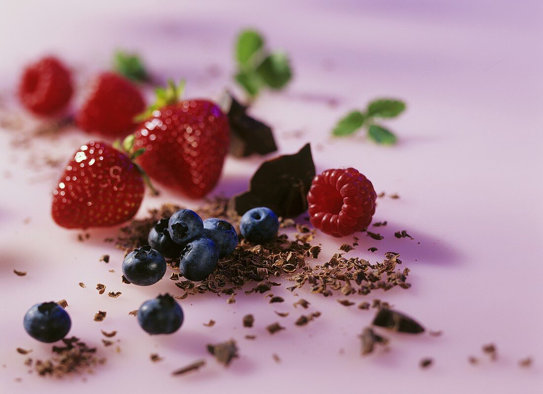 Stillleben mit Beeren und Schokolade auf rosa Untergrund