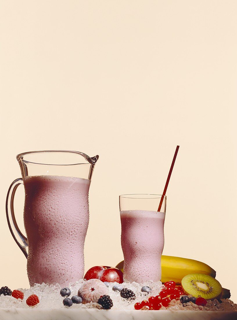 Ice-cooled berry shake in glass and jug