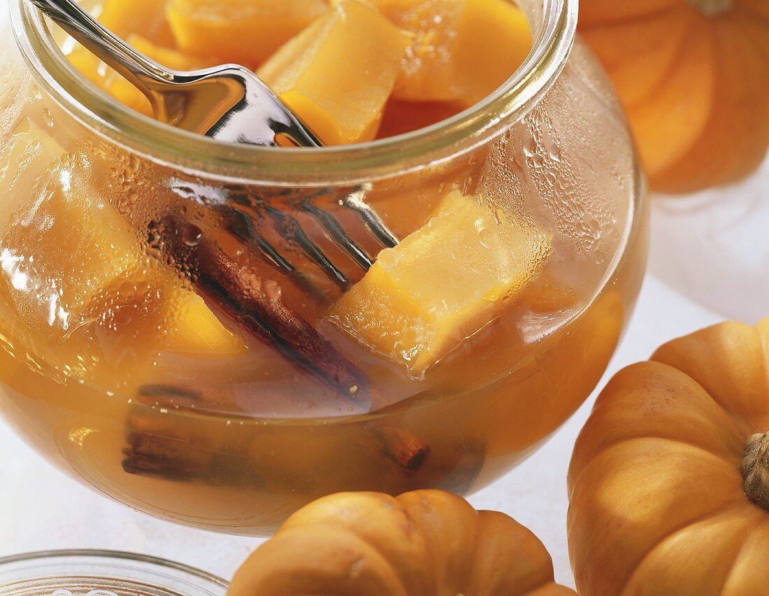 Orange pumpkin with cinnamon sticks in open jar with fork