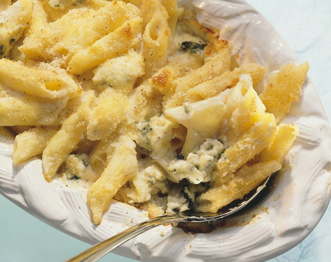 Penne bake with gorgonzola on white platter with spoon