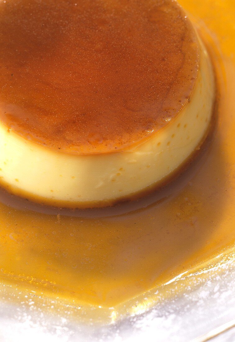 Creme caramel in Karamellsauce auf Glasteller mit Puderzucker