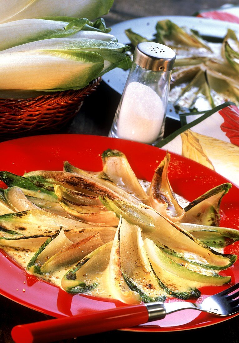 Baked chicory on red plate